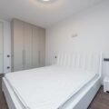 Bare mattress on a bed frame in a bright bedroom, ready for a mattress topper