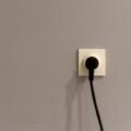 Electrical plug connected to a wall power outlet socket