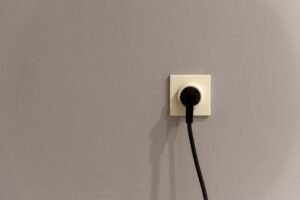 Electrical plug connected to a wall power outlet socket