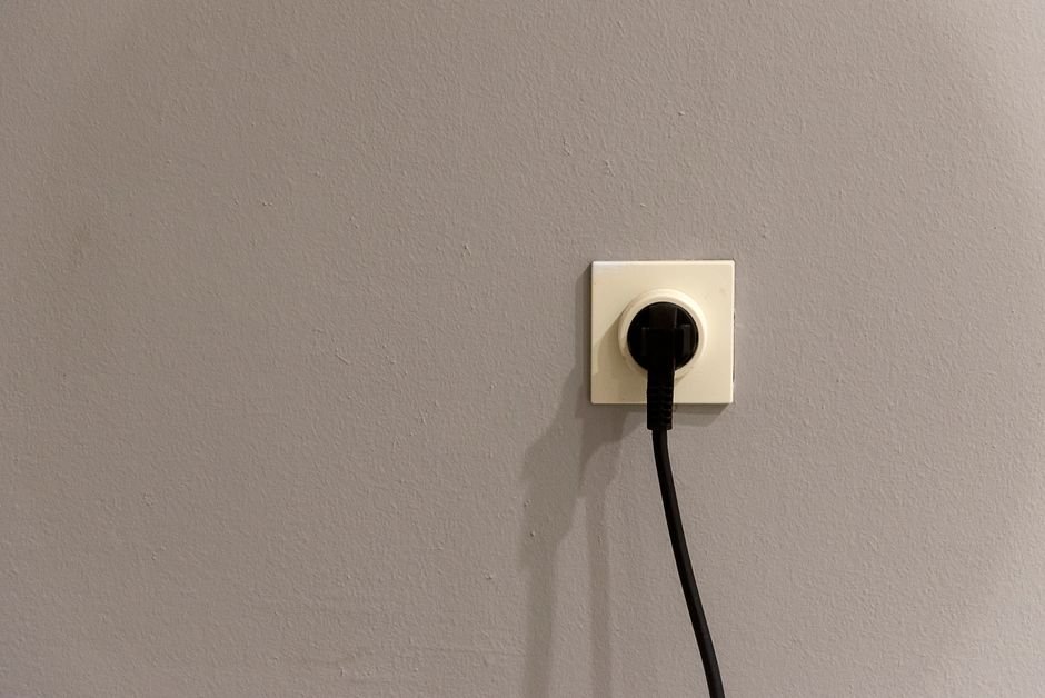 Electrical plug connected to a wall power outlet socket