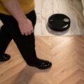 Robot vacuum cleaner with LiDAR sensor navigating a hardwood floor in a modern home