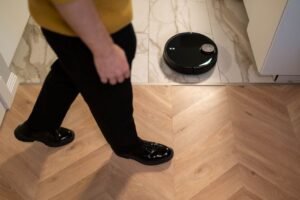Robot vacuum cleaner with LiDAR sensor navigating a hardwood floor in a modern home