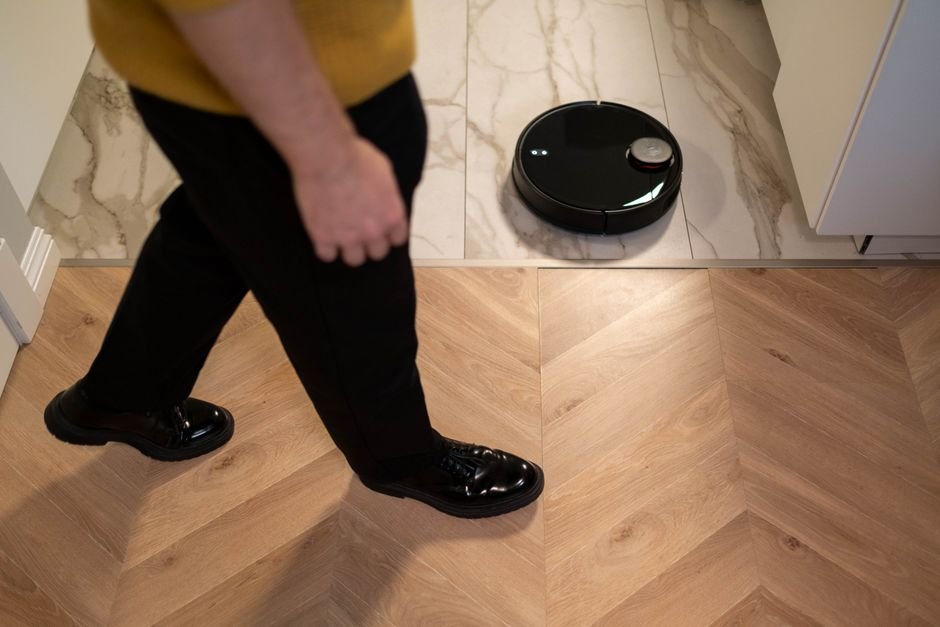 Robot vacuum cleaner with LiDAR sensor navigating a hardwood floor in a modern home