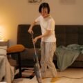 Person using a cordless stick vacuum to clean the floor of a living room