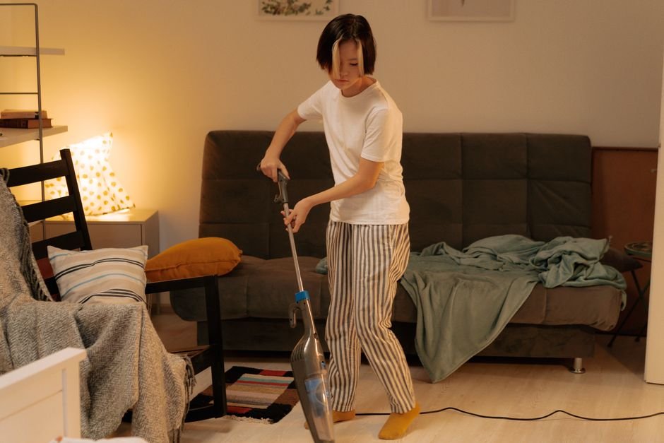 Person using a cordless stick vacuum to clean the floor of a living room