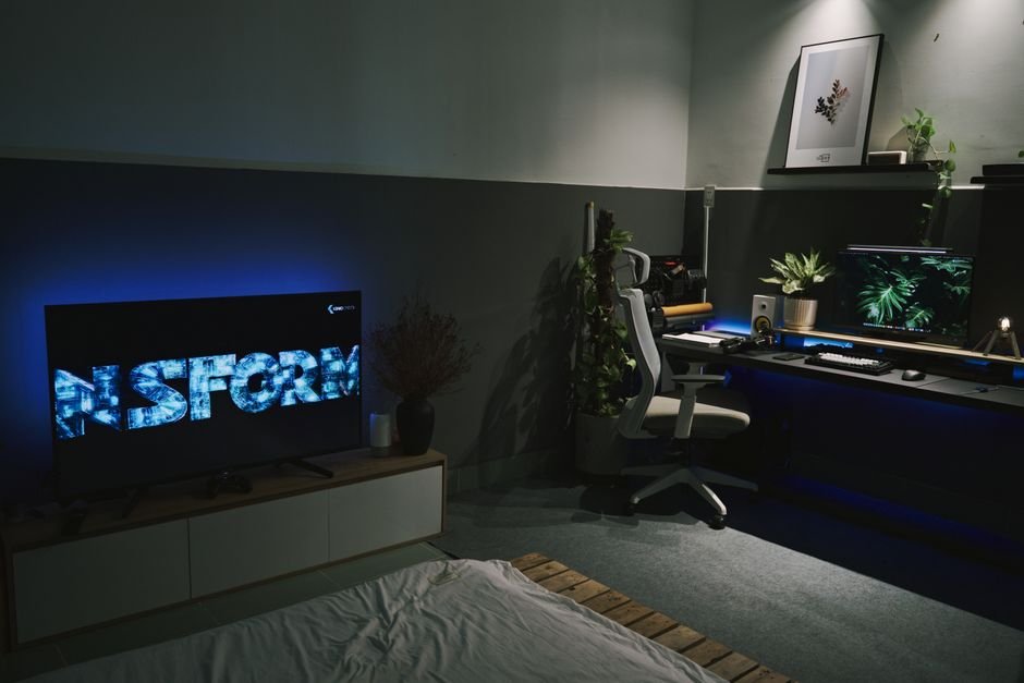 Room with smart LED light strip backlight glowing behind a TV and desk setup
