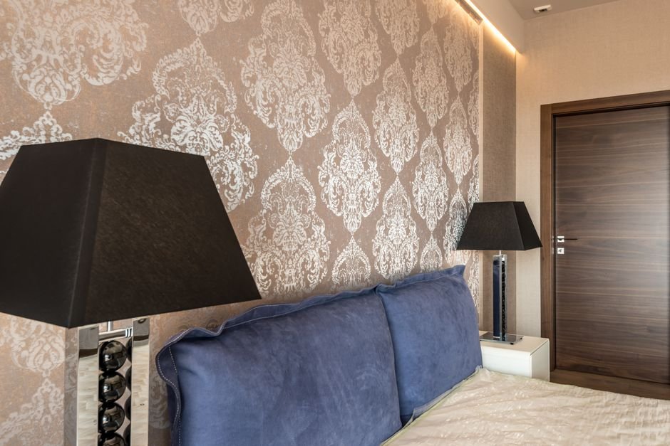 Damask wallpaper accent wall behind a bed