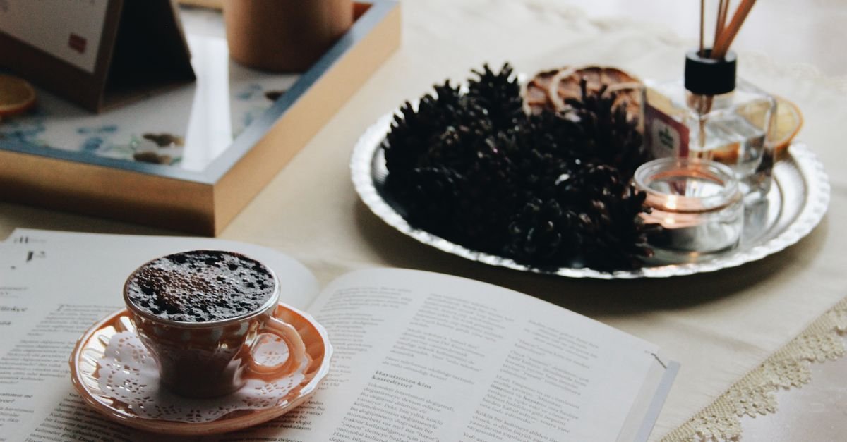 A tray holding a book, coffee cup and incense on a table