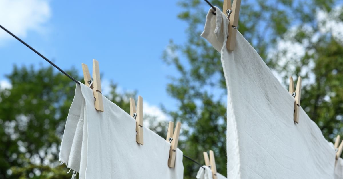 Fresh white laundry drying on a line under blue sky