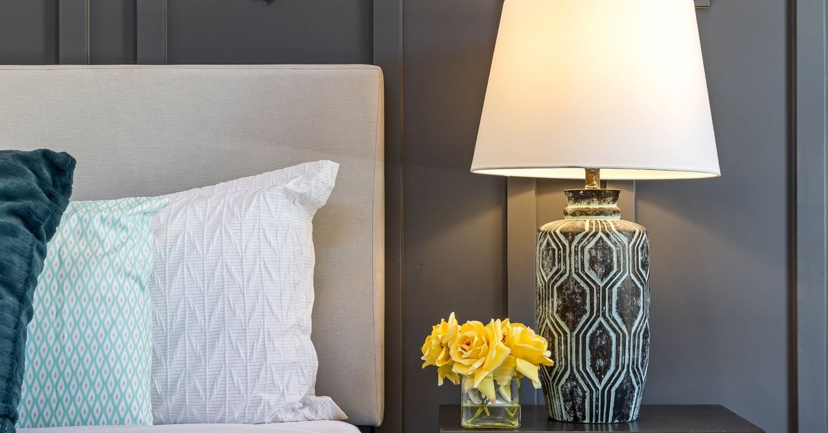 A styled nightstand with a lamp and flowers