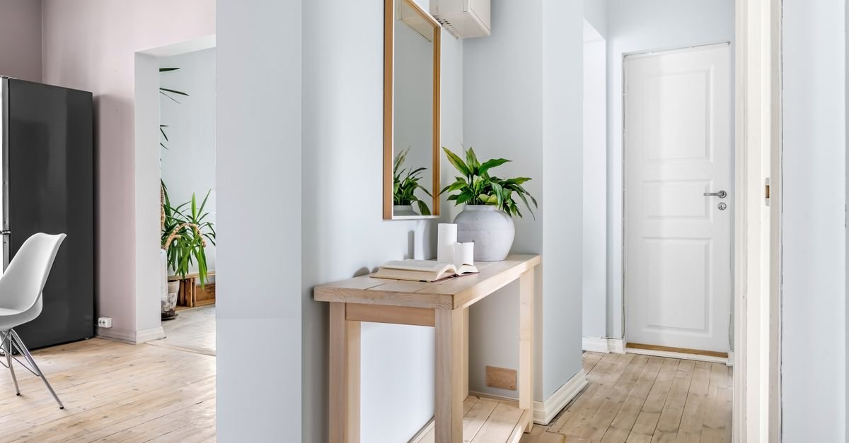A slim light-wood console with plants in a bright entrance