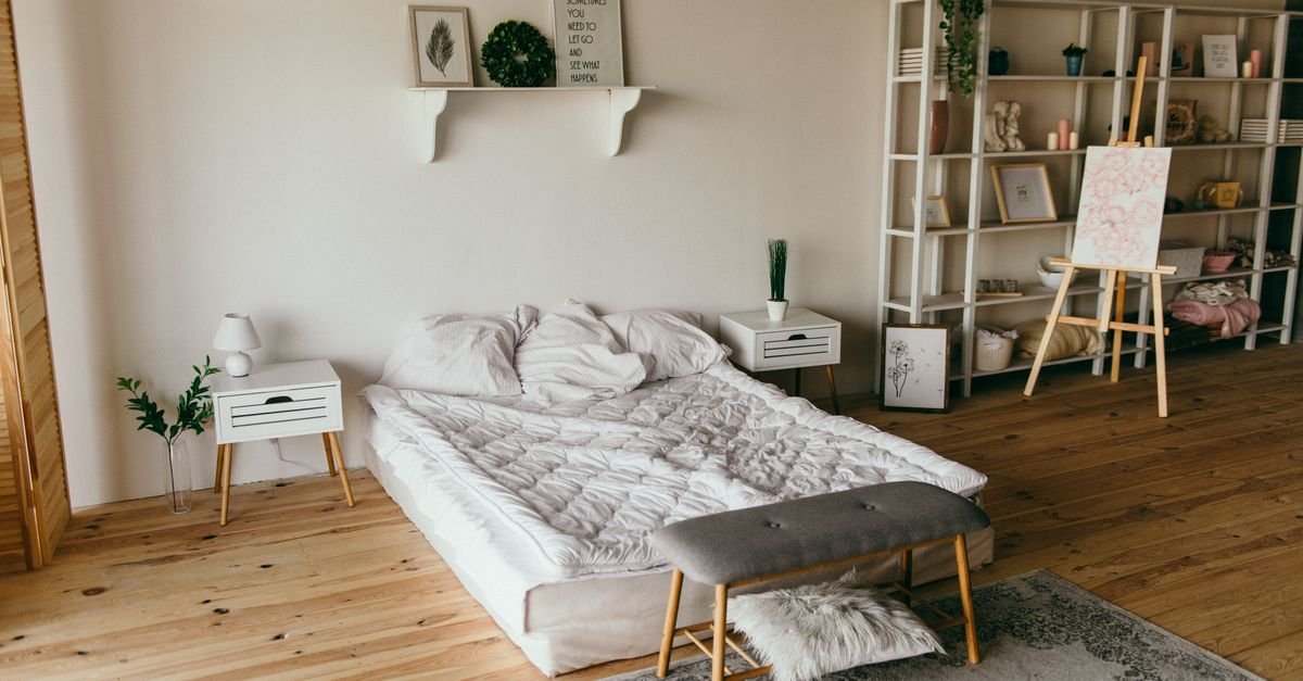 A small bedroom with light wood floors and open shelving