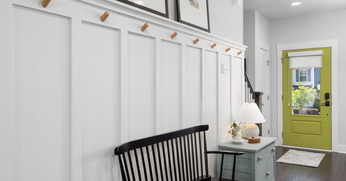 A peg rail and black bench in a white paneled entry