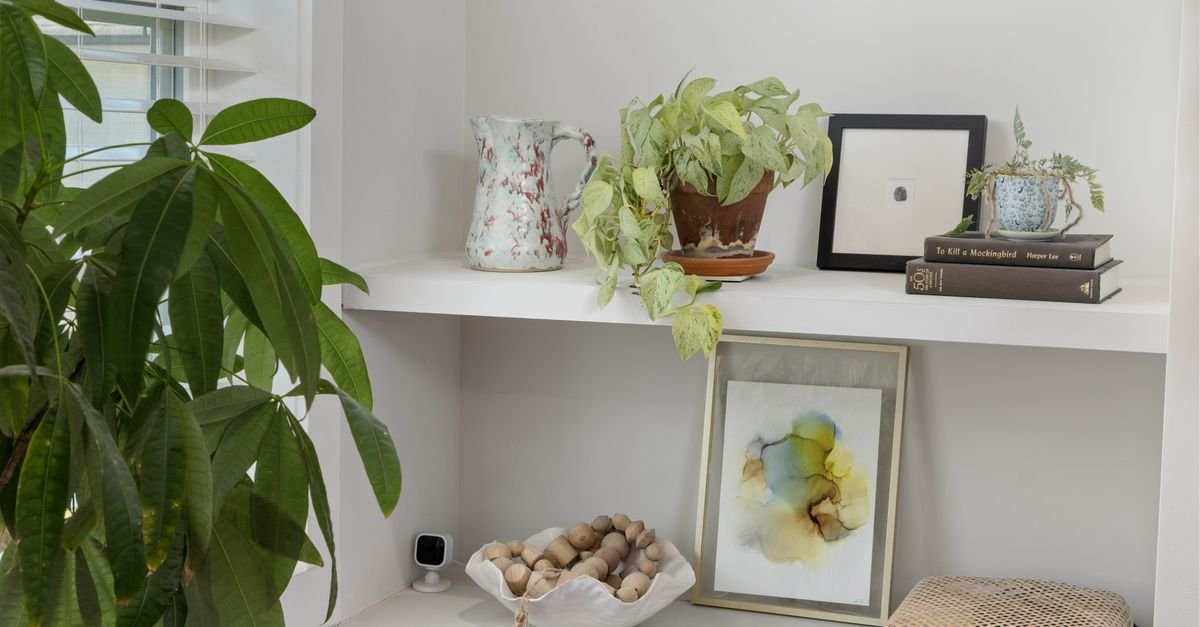 White floating shelves styled with plants, frames and a bowl