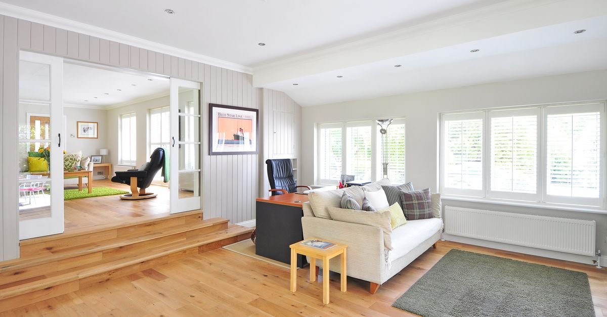 A bright room with pale oak flooring and white furniture