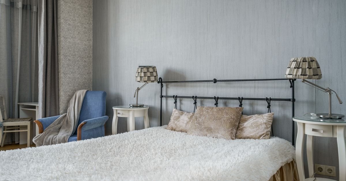 A neatly made bed with a white coverlet in a calm bedroom