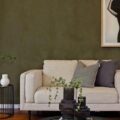 A styled living room with olive walls, cream sofa and layered decor