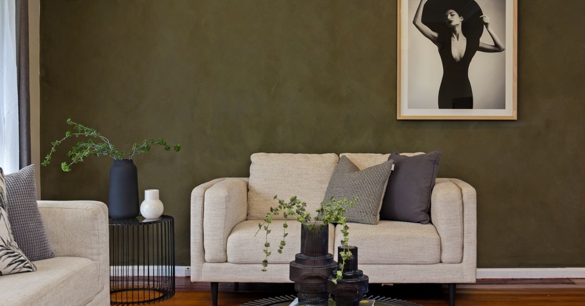 A styled living room with olive walls, cream sofa and layered decor