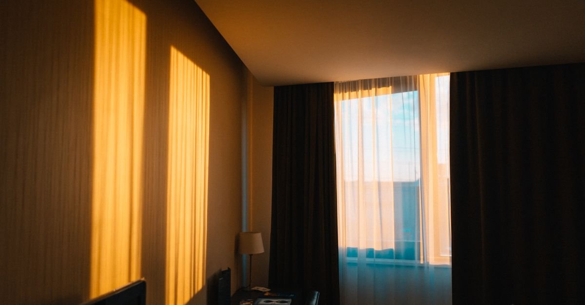 Golden evening light through high-hung bedroom curtains