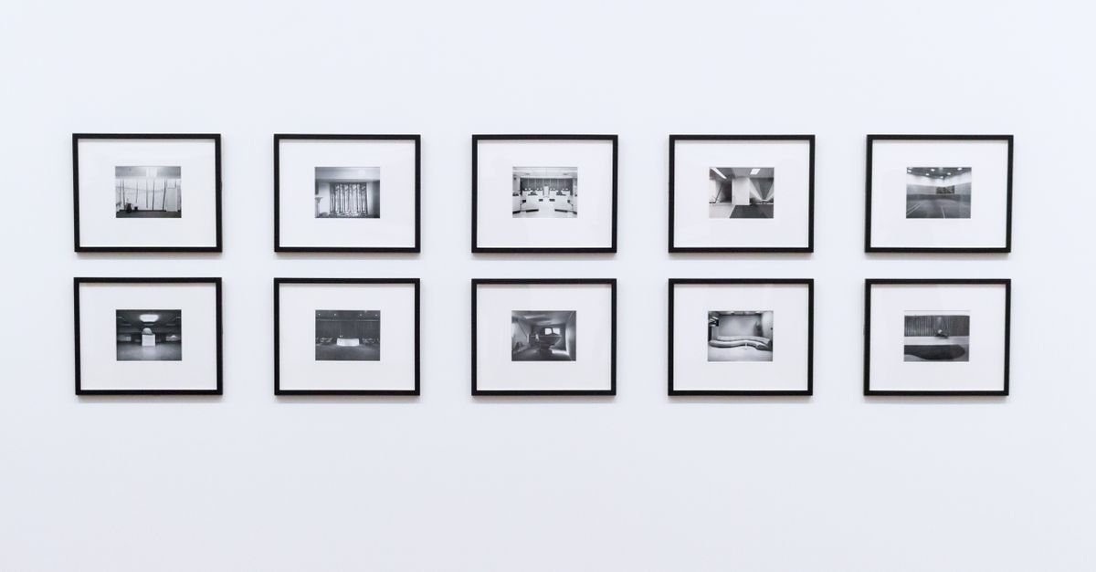 A neat grid of black-framed photographs on a white wall