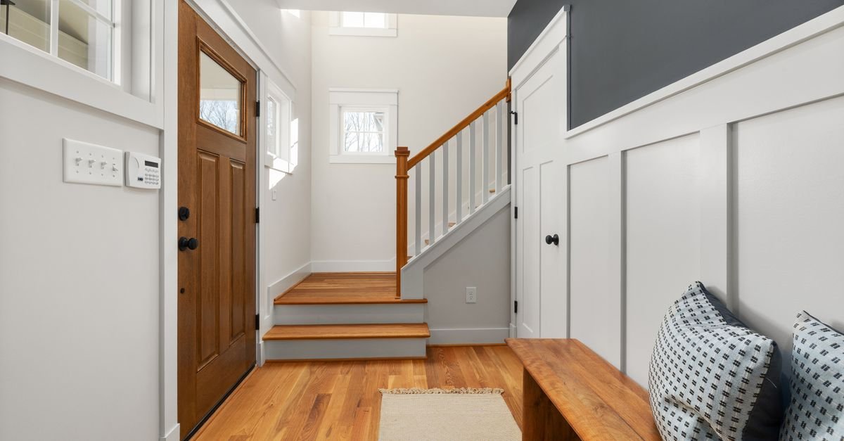 An entryway bench beside a wood front door and staircase