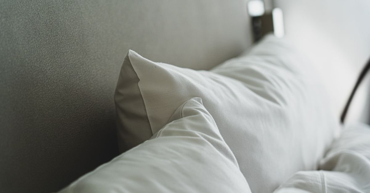 A crisp white pillow on a neatly made bed