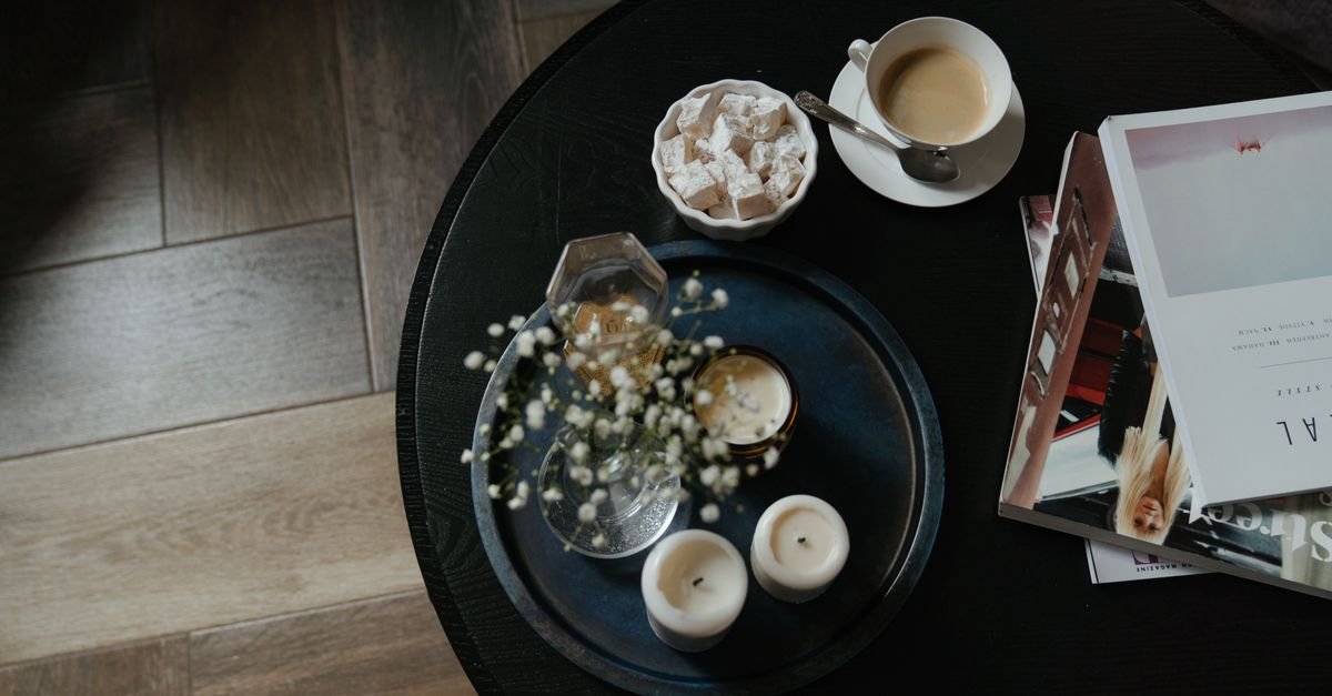 Top-down view of a black round tray styled with candles and coffee