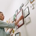 A woman arranging framed pictures into a gallery wall