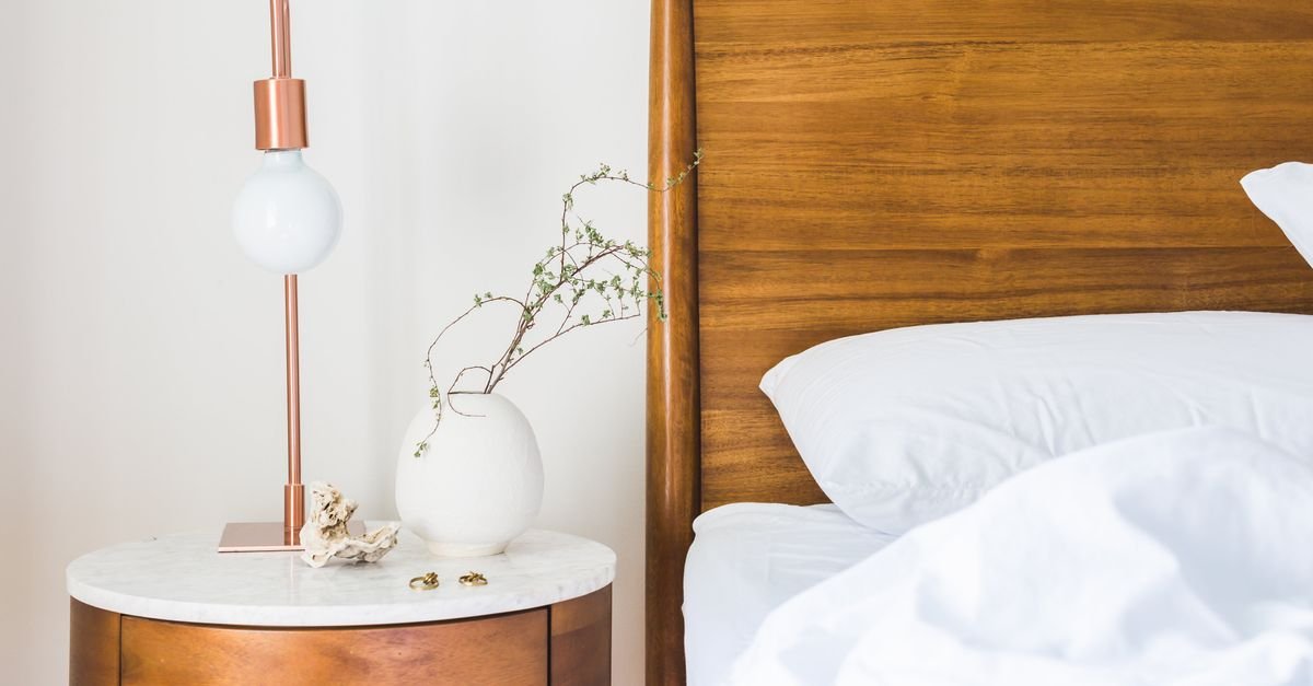 A round wood nightstand with a lamp