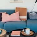 A styled living room with a blue sofa and round coffee tables holding books and candles
