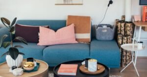A styled living room with a blue sofa and round coffee tables holding books and candles