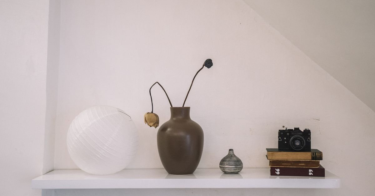 A minimal shelf vignette with a vase, paper lantern and vintage camera