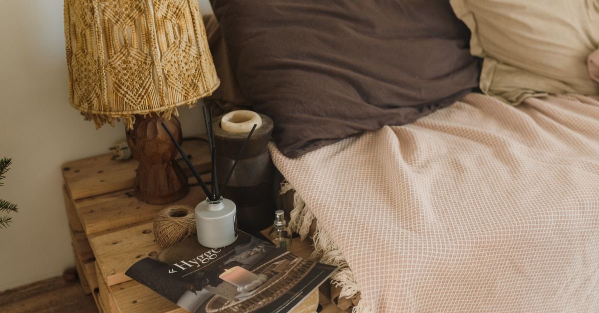 A rustic pallet nightstand with a lamp and magazines