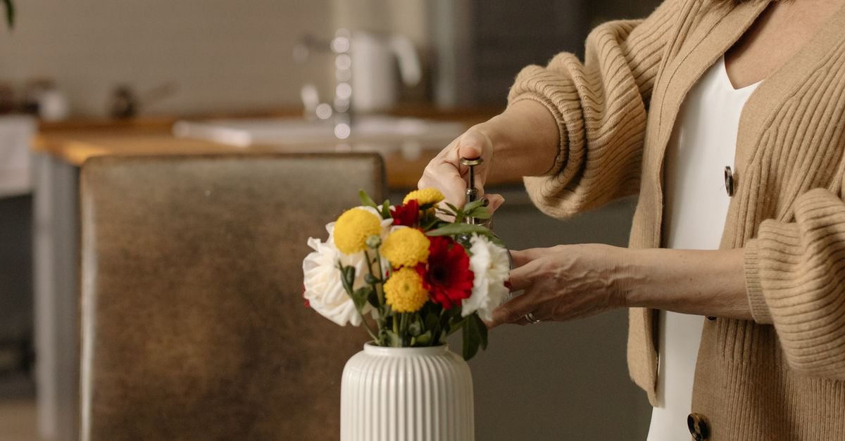 Hands arranging flowers in a ribbed vase