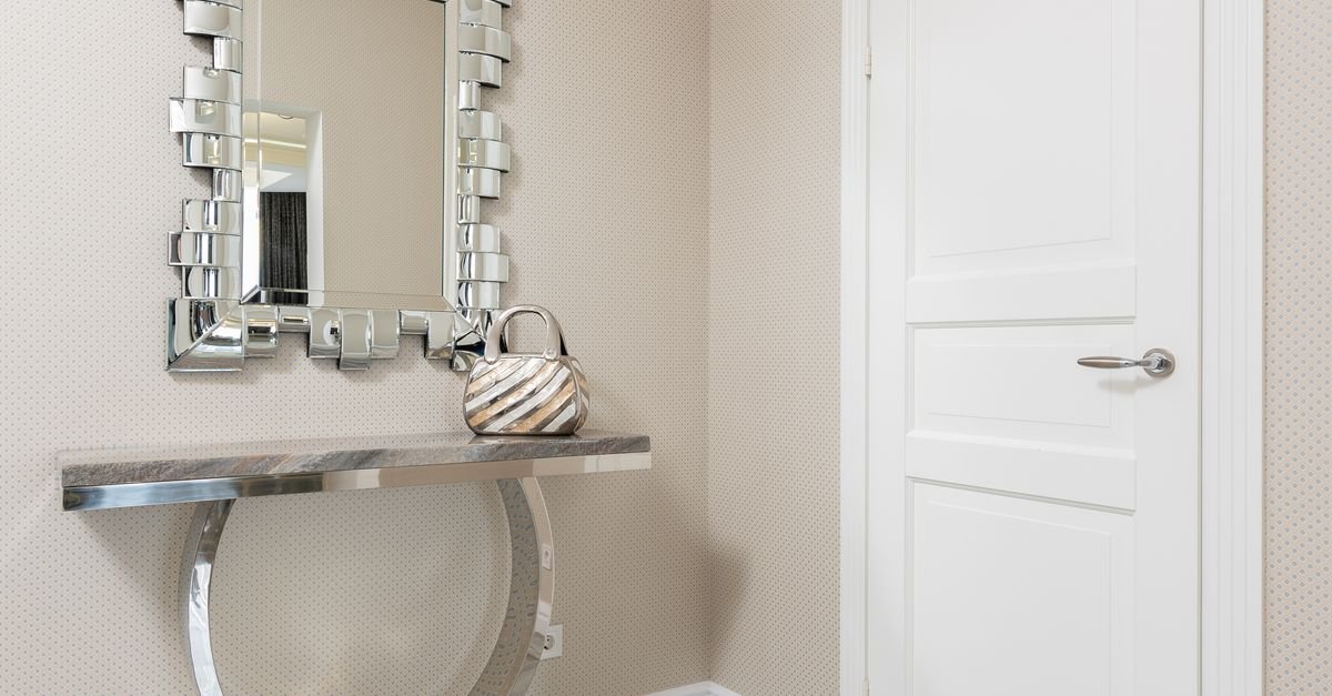 A silver demilune console beneath a decorative mirror