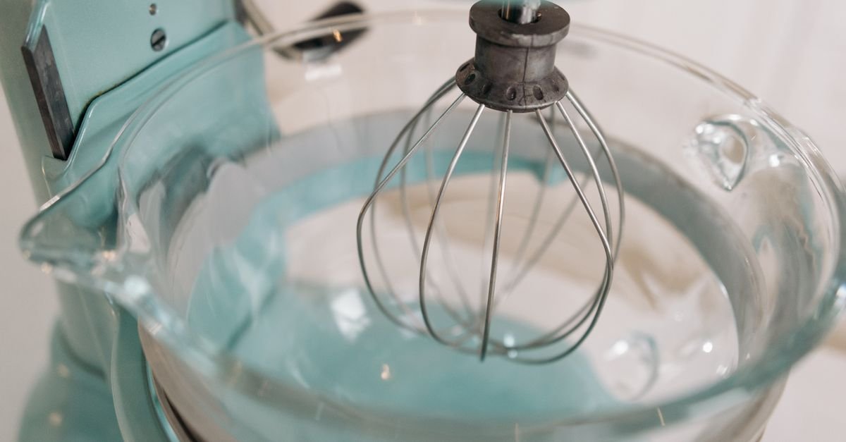 A stand mixer bowl with a whisk attachment
