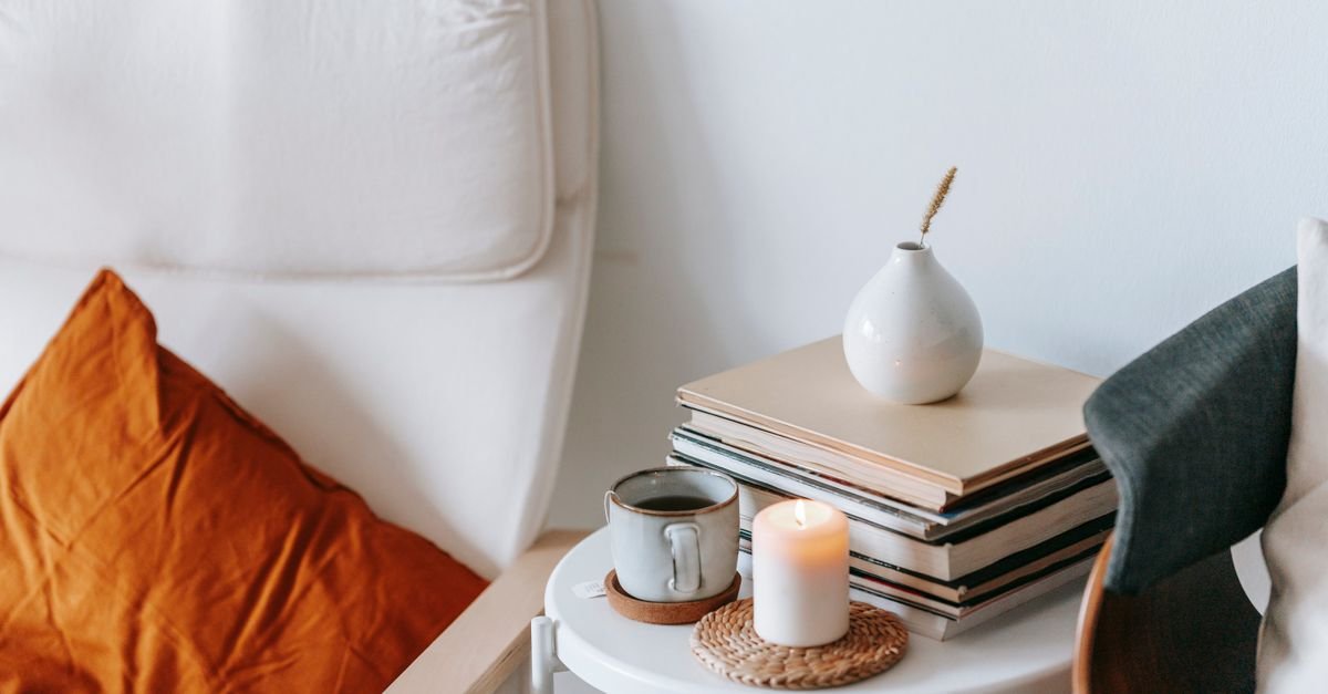 Candle burning beside books on a side table