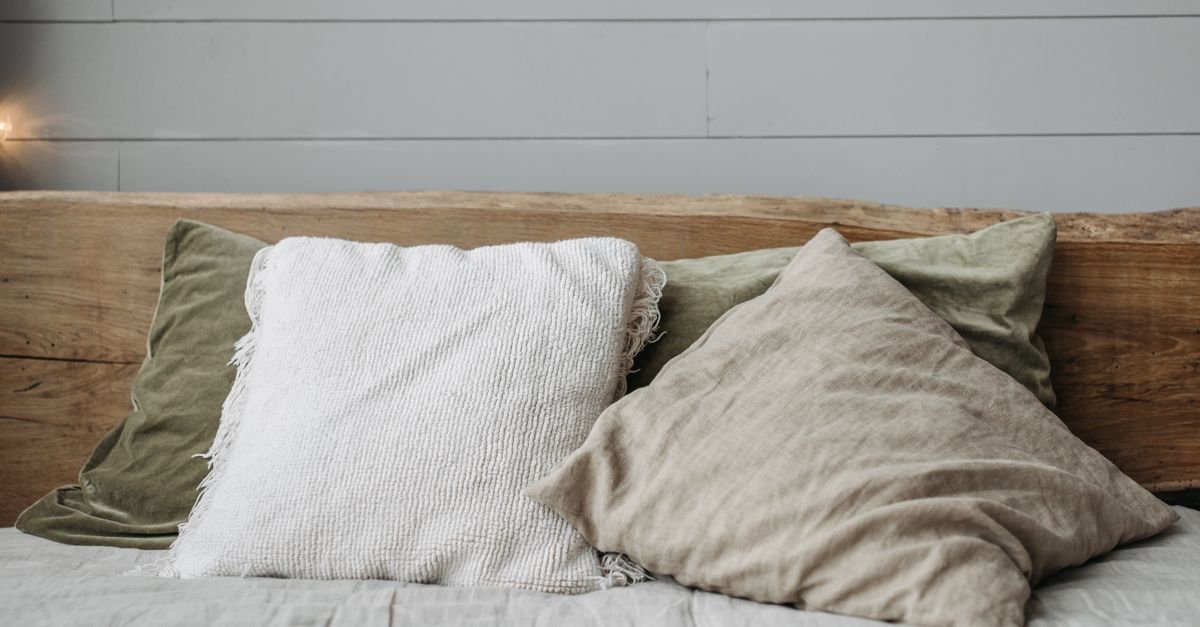 Neutral linen pillows layered against a wood headboard