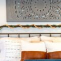 A designer bed with black iron frame, layered white bedding and leather and blue pillows