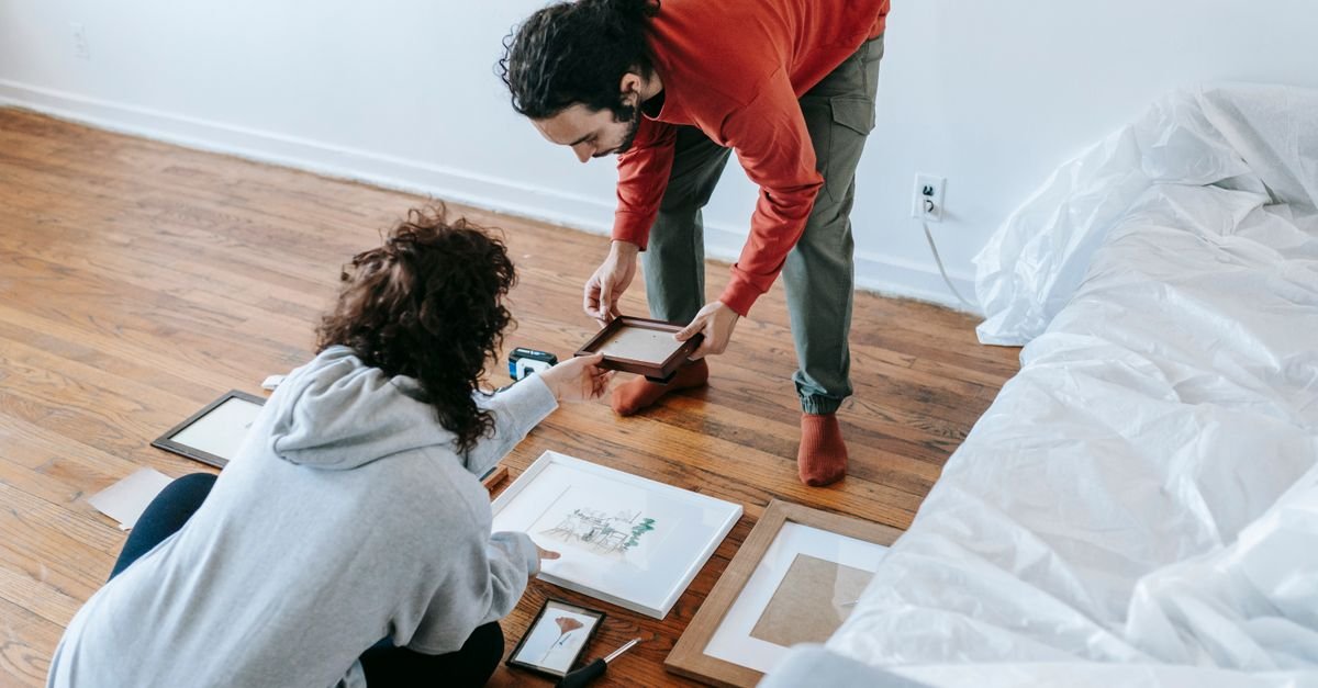 A couple arranging framed art on the floor