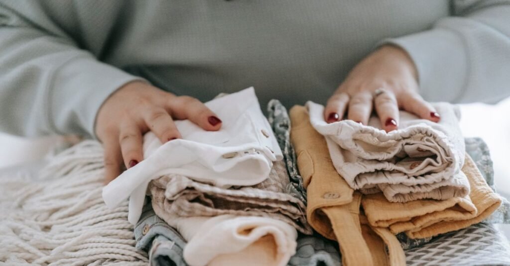 Hands folding stacks of baby clothes