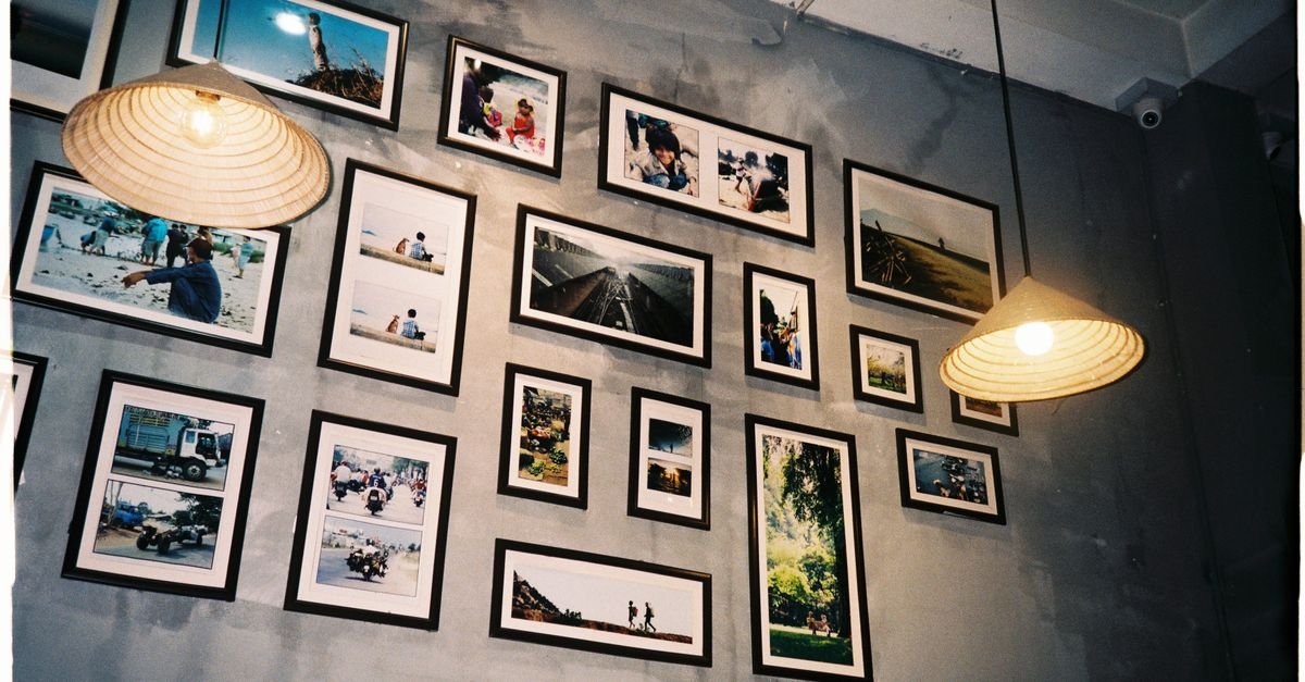 A dense gallery wall of framed photographs with pendant lamps