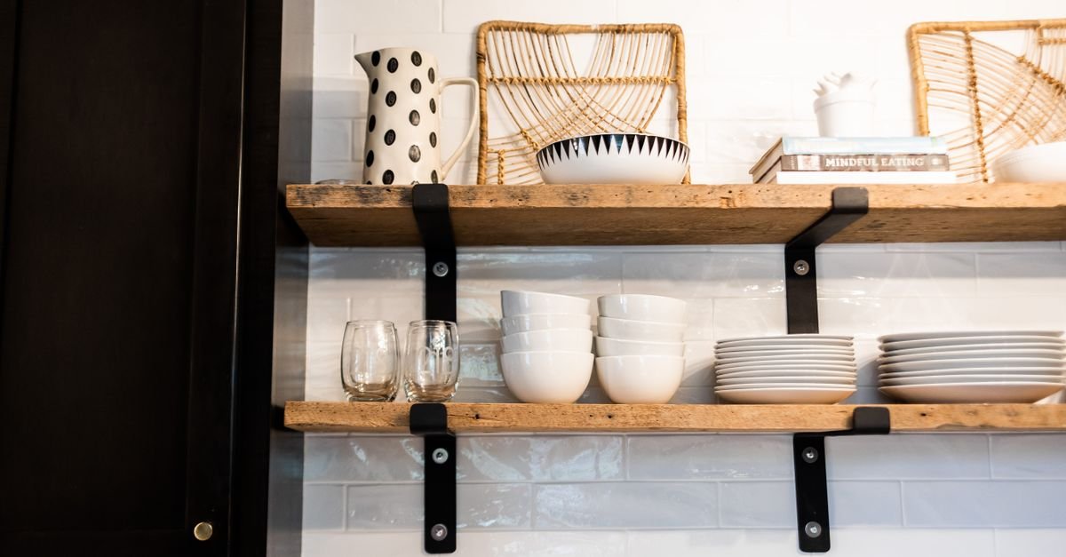 Open kitchen shelves with stacked white dishes and baskets