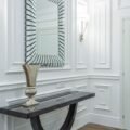 An elegant entryway with a dark console table and patterned mirror on panel molding
