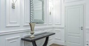 An elegant entryway with a dark console table and patterned mirror on panel molding