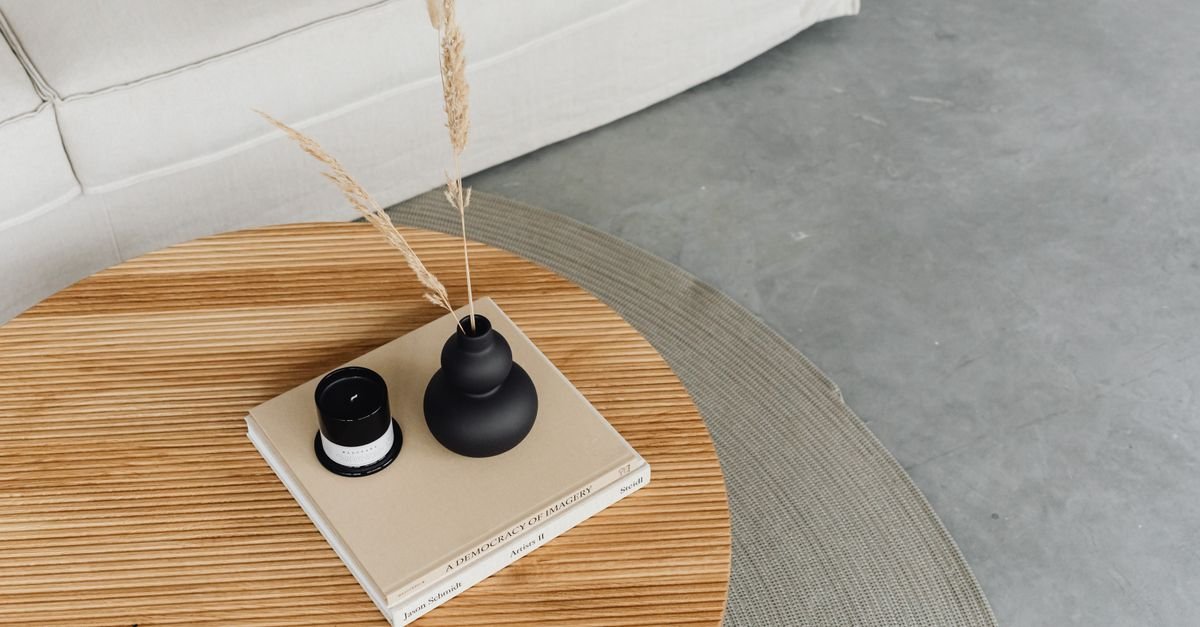 A light wood coffee table styled minimally with books and black candle holders