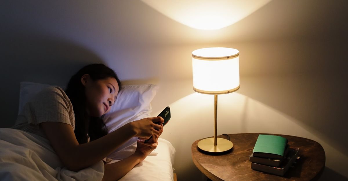 A woman reading in bed beside a glowing lamp