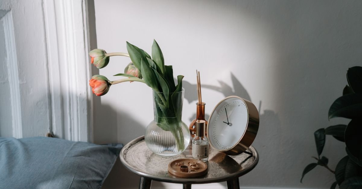 A round bedside table with tulips and a small clock