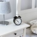 A white nightstand with a drawer and lamp