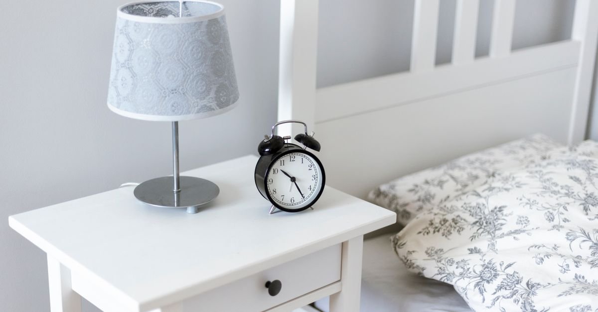 A white nightstand with a drawer and lamp